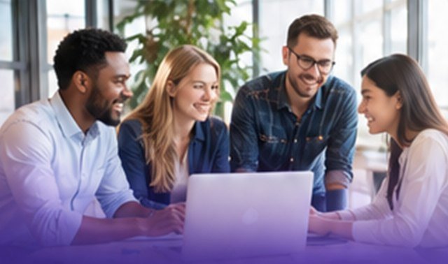 Four colleagues smiling together around a laptop